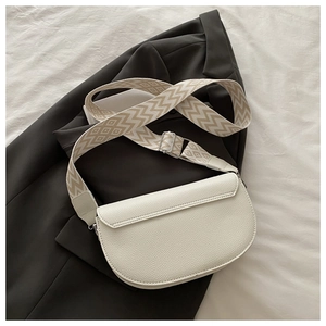 Détail du sac selle blanc texture litchi avec large bandoulière en toile géométrique