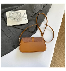 Detail of caramel brown crossbody bag with woven texture flap and gold metal hardware