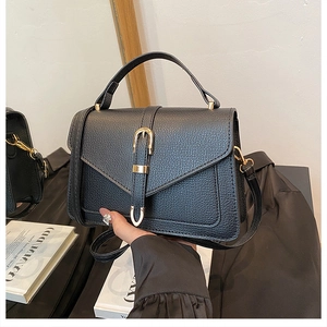 Detail of vintage black leather handbag with gold horseshoe buckle and top handle