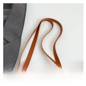 Close-up of woven straw tote bag with brown PU leather handle and detailed stitching