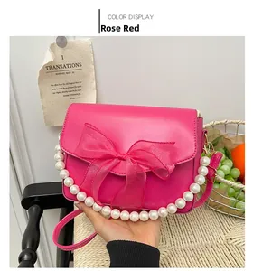 Detail of rose red shoulder bag featuring large mesh bow and elegant pearl chain strap