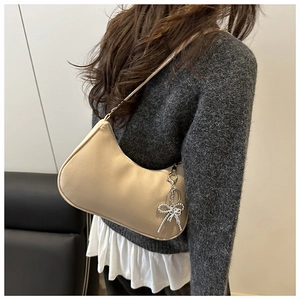 Dettaglio della borsa hobo a mezzaluna beige con ciondolo decorativo a fiocco