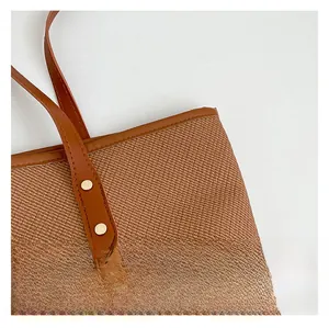 Detailed view of brown woven texture and leather handle with gold rivets on tote bag