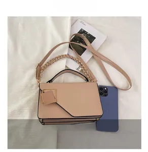 Macro-opname van beige crossbodytas met kettingriem en geometrische gouden gesp detail