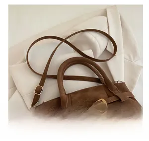 Detail view of brown suede tote bag featuring a decorative buckle and adjustable strap