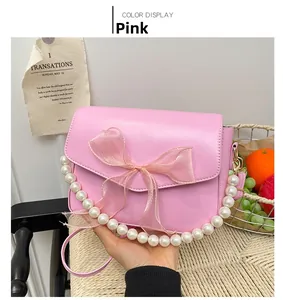 Detail view of pink glossy bag with large mesh bow and decorative pearl chain handle