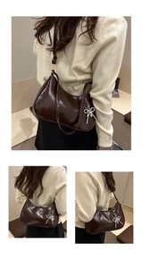 Detail of dark brown semi-moon shoulder bag with silver beaded bow charm accessory