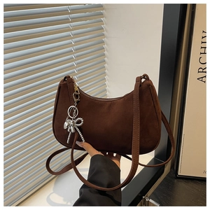 Brown suede crescent bag detail with silver beaded bow pendant and fine shoulder strap