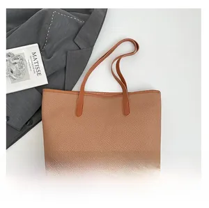 Detailed top view of a brown woven tote bag with smooth leather trim and straps