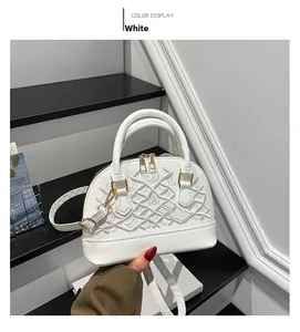 Detail view of white shell-shaped handbag with exquisite embroidery and gold hardware