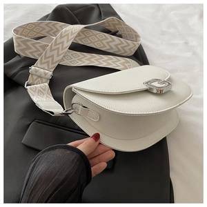 Détail du sac selle en cuir grainé blanc avec boucle G et bandoulière tissée géométrique