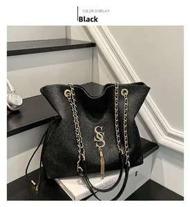 Detail der schwarzen Shopper-Tasche mit glitzerndem Stoff und goldener Kette mit S-Anhänger