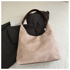 Detailansicht der beigen Wildleder-Hobo-Tasche mit grauem Blazer und Kunstbuch