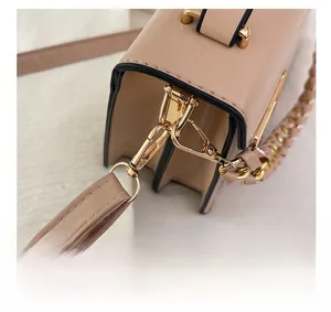 Detailweergave van de gouden metalen accessoires en afneembare haken op de beige leren tas