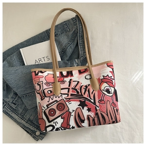 Flat lay detail of a graffiti print tote bag with street art patterns and leather straps