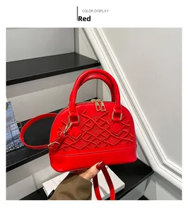 Detail of red shell handbag with textured embroidery, gold zippers and shoulder strap