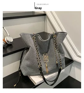 Detailansicht der grauen Pailletten-Tasche mit goldenem S-Logo, Quaste und Kette