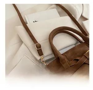 Detail showing adjustable brown suede shoulder strap with golden metal buckle and hook