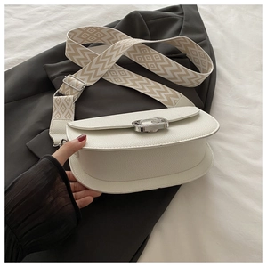 Détail du sac selle blanc avec texture litchi et large bandoulière géométrique