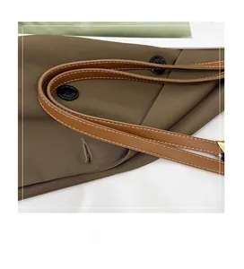 Détail de la poignée en cuir marron avec surpiqûres blanches et boutons noirs