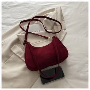 Detail of burgundy frosted suede shoulder bag featuring adjustable strap and metal hardware