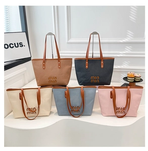 Detail view of five canvas tote bags with leather handles and textured stripe design