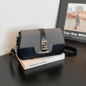 Chic saddle crossbody bag with mixed texture and gold buckle on a minimalist setting