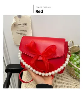 Close-up of bright red crossbody bag with large chiffon bow and pearl chain handle