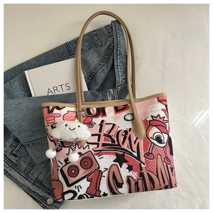 Detail of graffiti print tote bag with plush cloud charm and slim shoulder straps