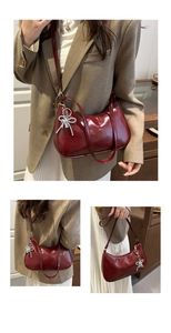 Detail of burgundy half-moon underarm bag with glossy leather and rhinestone bow charm