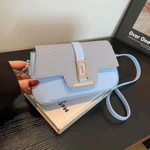 Light blue crossbody saddle bag with woven grey flap and golden geometric buckle clasp