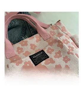 Close-up of pink floral canvas tote bag with woven label and cotton webbing handles