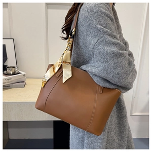 Détail d'un grand sac cabas marron avec foulard en soie jaune décoratif sur la poignée