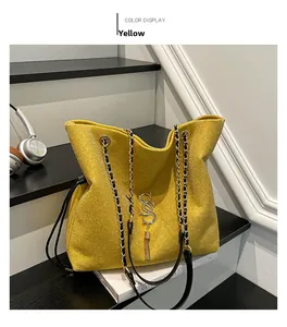 Detail der gelben Glitzer-Beuteltasche mit Kettenriemen und goldfarbenem Quastenanhänger