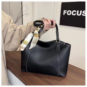 Détail du sac cabas noir avec surpiqûres blanches et foulard à fleurs sur bois
