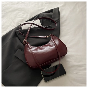 Macro shot of dark red underarm bag with smooth glossy faux leather texture