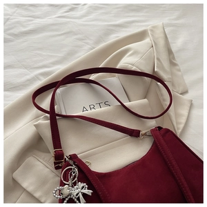 Detail of burgundy frosted suede crescent bag with silver heart and bow pendants