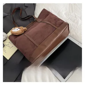 Détail du grand sac cabas marron avec charme de lion et texture en daim doux