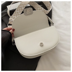 Détail du sac selle blanc en demi-lune avec cuir texturé et sangle géométrique
