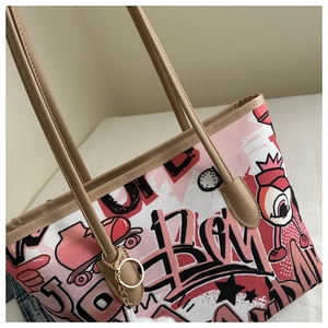 Detail of pink graffiti canvas tote with brown leather trim and golden metal charm