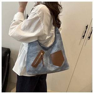 Detail der blauen Denim-Tasche mit braunen Ledertaschen und verstellbarem Schultergurt