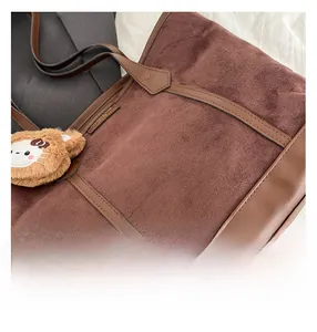 Détails de la texture en daim marron foncé et cuir avec un pendentif en peluche chic
