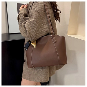 Détail d'un sac cabas marron avec surpiqûres blanches et foulard en soie décoratif