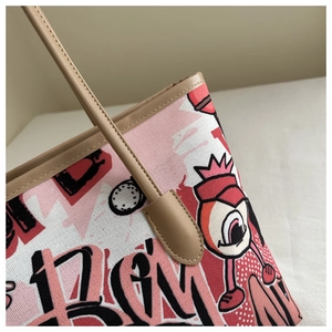 Detail of pink canvas tote bag with graffiti print and khaki leather shoulder strap