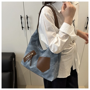 Detail der blauen Denim-Tasche mit braunem Lederbesatz und Metallreißverschluss