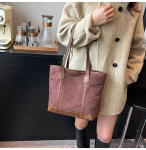 Détail du grand sac cabas bordeaux avec garniture en cuir brun sur un manteau beige