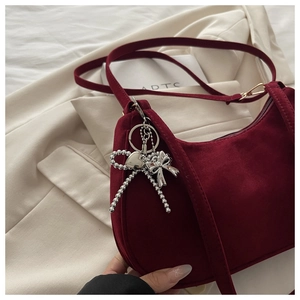 Detail view of burgundy frosted half-moon bag with silver bow and heart charm
