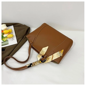 Détail d'un sac cabas en cuir marron avec foulard décoratif et surpiqûres blanches
