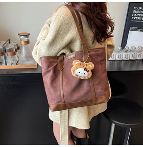 Détail du sac cabas en daim marron avec garniture en cuir et breloque ours