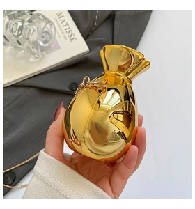 Dettaglio di una borsa a mano dorata a forma di sacchetto con catena su un blazer elegante